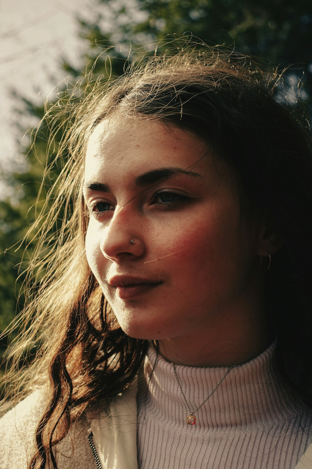 Portrait of a young woman with light brown hair smiling outdoors